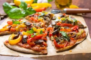 Whole wheat pita bread topped with vegetables and melted cheese, ready to bake 